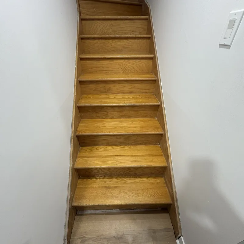 Escalier en bois verni orangé avant les travaux